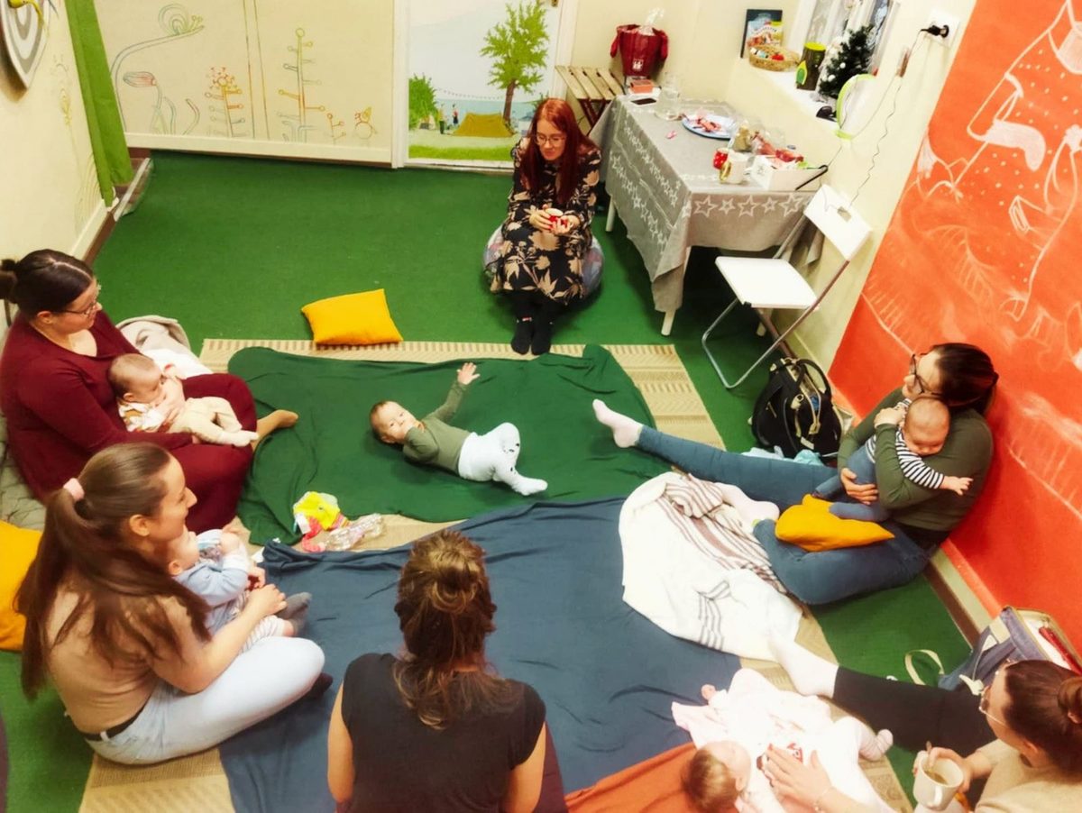Anyatársalgó: kisbabás anyukák beszélgetnek körben ülve, a babák a takarókon játszanak