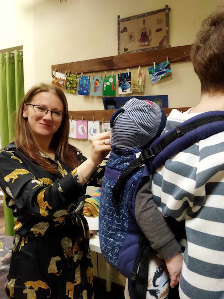 Hordozóeszköz próba: formázott hordozó beállítása, a tanácsadó a kisbaba fejtámaszát igazítja